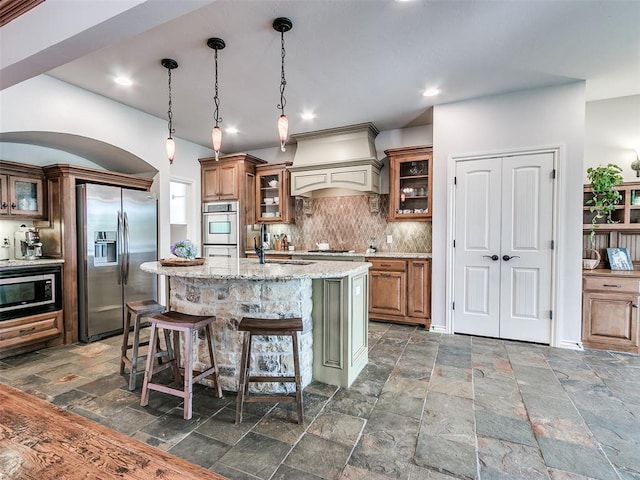 7612 NW 134th St, Oklahoma City, OK 73142 - kitchen featuring stainless steel appliances, stone tile flooring, brown cabinets, tasteful backsplash, and recessed lighting