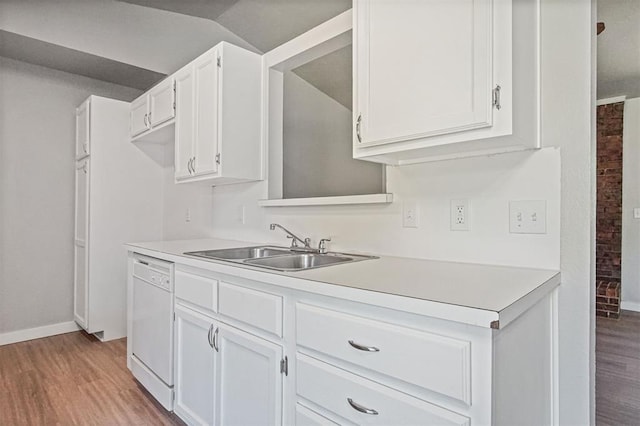 kitchen featuring dishwasher, a sink, light wood finished floors, and light countertops