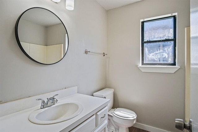 bathroom with vanity, toilet, wood finished floors, and baseboards