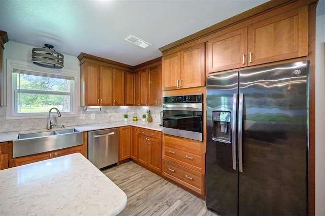 2590 Old 21 Rd, Idabel, OK 74745 - kitchen featuring stainless steel appliances, a sink, brown cabinetry, light countertops, and tasteful backsplash