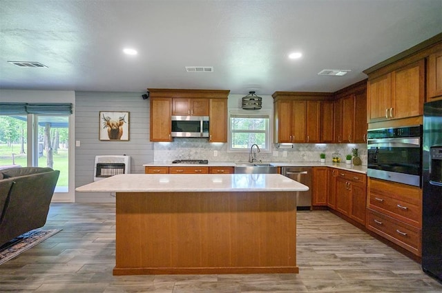 2590 Old 21 Rd, Idabel, OK 74745 - kitchen with appliances with stainless steel finishes, a kitchen island, light countertops, light wood-style floors, and tasteful backsplash