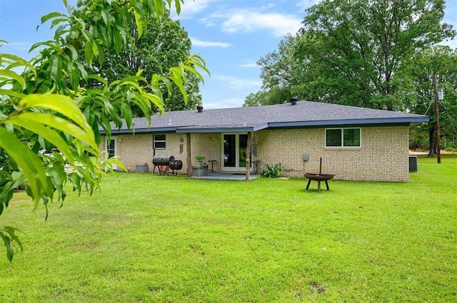 2590 Old 21 Rd, Idabel, OK 74745 - back of house featuring a lawn, brick siding, a shingled roof, central AC unit, and a patio area