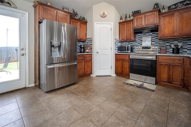 1528 Fawn Run Xing, Norman, OK 73071 - kitchen featuring appliances with stainless steel finishes, under cabinet range hood, decorative backsplash, brown cabinets, and vaulted ceiling