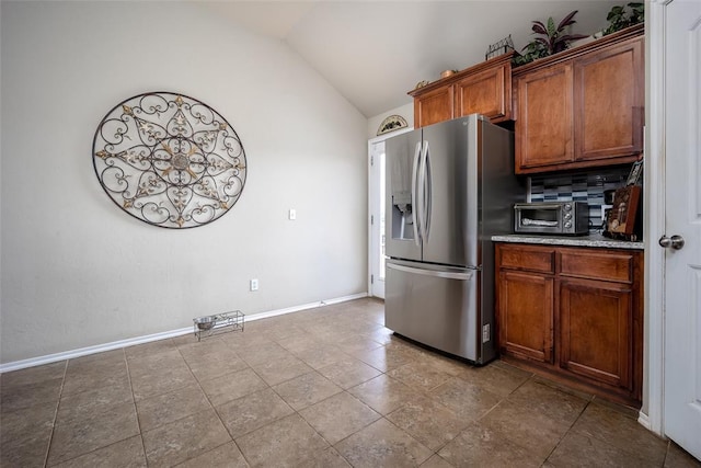 1528 Fawn Run Xing, Norman, OK 73071 - kitchen with stainless steel refrigerator with ice dispenser, vaulted ceiling, brown cabinetry, baseboards, and backsplash