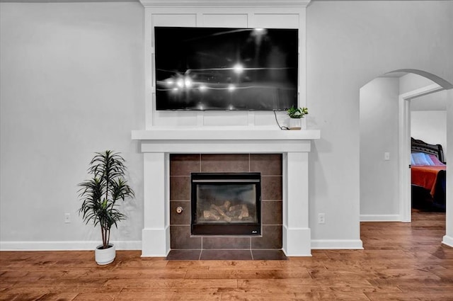 12824 NW 4th Ter, Yukon, OK 73099 - detailed view of a tile fireplace, arched walkways, baseboards, and wood finished floors