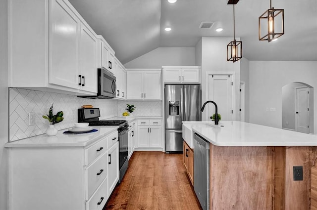 12824 NW 4th Ter, Yukon, OK 73099 - kitchen featuring appliances with stainless steel finishes, arched walkways, vaulted ceiling, wood finished floors, and light countertops