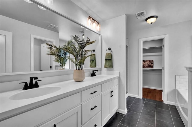 12824 NW 4th Ter, Yukon, OK 73099 - full bathroom with double vanity, tile patterned floors, a tub, a spacious closet, and baseboards
