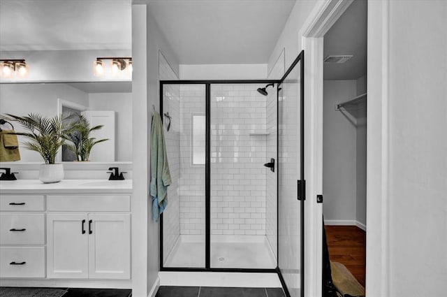 12824 NW 4th Ter, Yukon, OK 73099 - bathroom featuring double vanity, a shower stall, baseboards, and a walk in closet