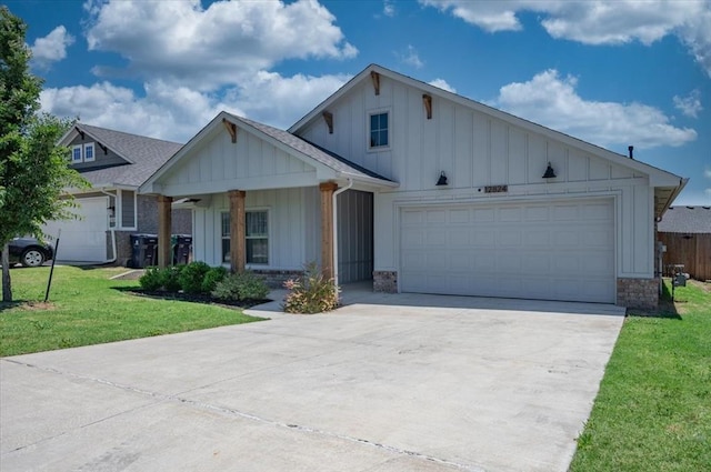 12824 NW 4th Ter, Yukon, OK 73099 - view of front facade with board and batten siding, driveway, a front yard, a garage, and covered porch