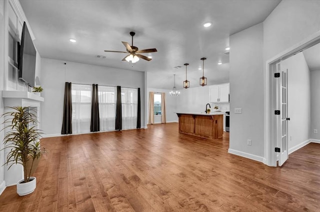 12824 NW 4th Ter, Yukon, OK 73099 - unfurnished living room featuring a ceiling fan, light wood-type flooring, a chandelier, recessed lighting, and a fireplace