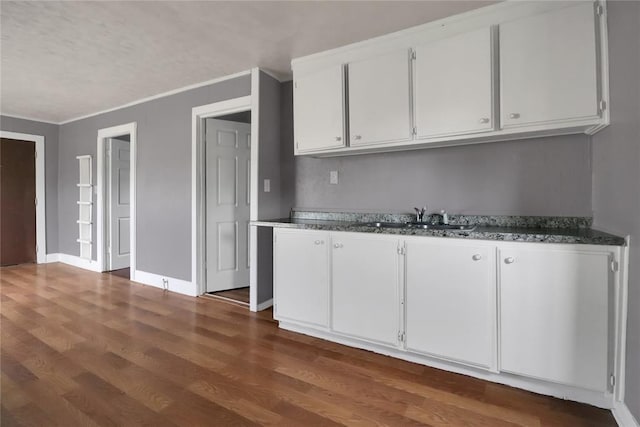 6017 Pat Ave, Oklahoma City, OK 73149 - kitchen with a sink, dark wood finished floors, white cabinets, baseboards, and ornamental molding