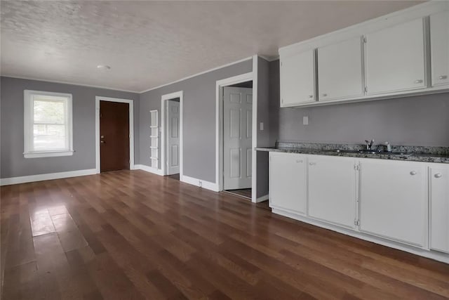 6017 Pat Ave, Oklahoma City, OK 73149 - kitchen with a sink, dark wood finished floors, baseboards, white cabinets, and a textured ceiling