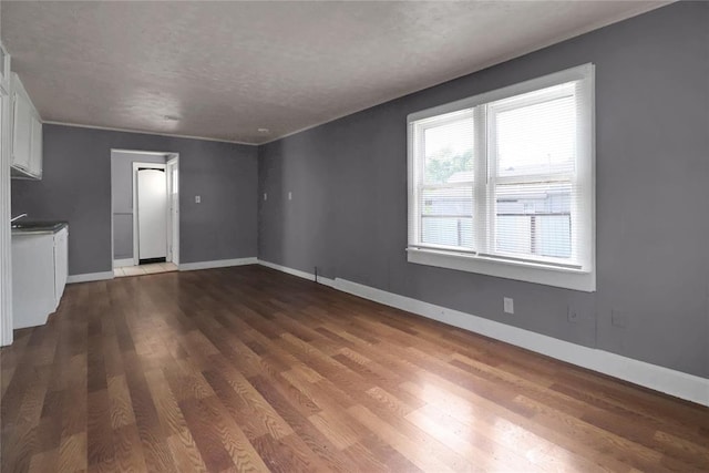 6017 Pat Ave, Oklahoma City, OK 73149 - unfurnished living room featuring dark wood finished floors, baseboards, and a textured ceiling
