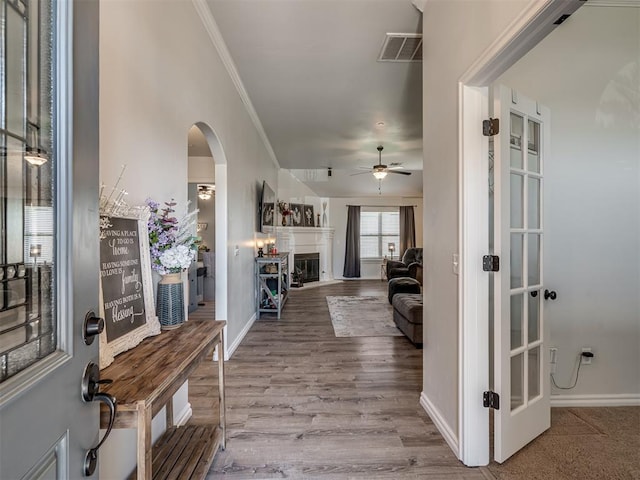 12005 NW 139th St, Piedmont, OK 73078 - foyer featuring arched walkways, crown molding, ceiling fan, a fireplace, and wood finished floors