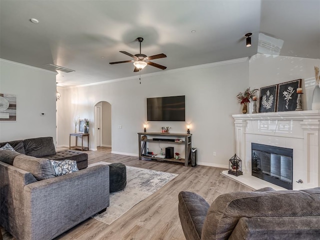 12005 NW 139th St, Piedmont, OK 73078 - living room featuring arched walkways, a ceiling fan, wood finished floors, a tile fireplace, and crown molding
