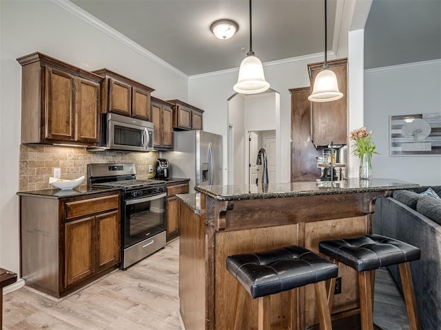 12005 NW 139th St, Piedmont, OK 73078 - kitchen featuring appliances with stainless steel finishes, a kitchen bar, crown molding, light wood finished floors, and dark stone countertops