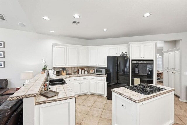 1701 Tifton Dr, Edmond, OK 73012 - kitchen with black appliances, tile countertops, a sink, recessed lighting, and decorative backsplash