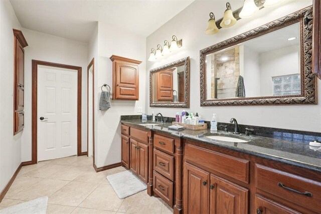 1701 Tifton Dr, Edmond, OK 73012 - bathroom featuring double vanity, a tile shower, tile patterned floors, and baseboards