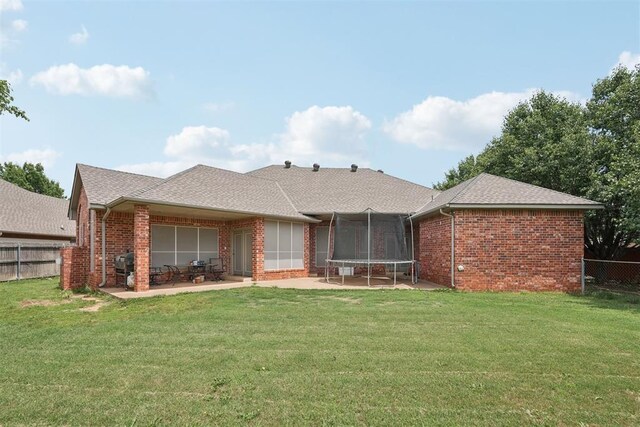 1701 Tifton Dr, Edmond, OK 73012 - back of house featuring brick siding, a patio area, a trampoline, and roof with shingles