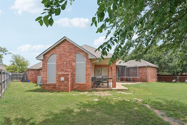 1701 Tifton Dr, Edmond, OK 73012 - back of property with a trampoline, brick siding, a patio, a shingled roof, and central air condition unit