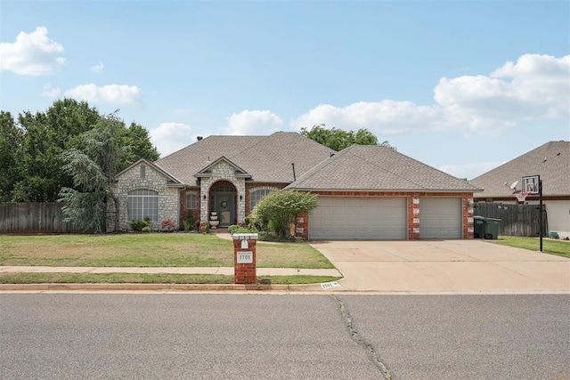 1701 Tifton Dr, Edmond, OK 73012 - french country style house with an attached garage, concrete driveway, brick siding, stone siding, and roof with shingles