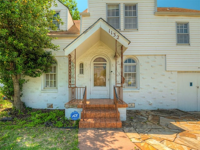 1132 SW 25th St, Oklahoma City, OK 73109 - doorway to property featuring brick siding and a shingled roof