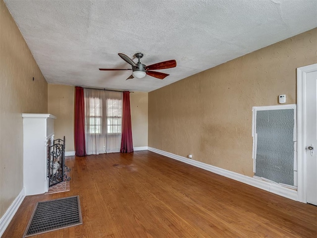 1132 SW 25th St, Oklahoma City, OK 73109 - unfurnished living room with a ceiling fan, a textured ceiling, wood finished floors, and baseboards