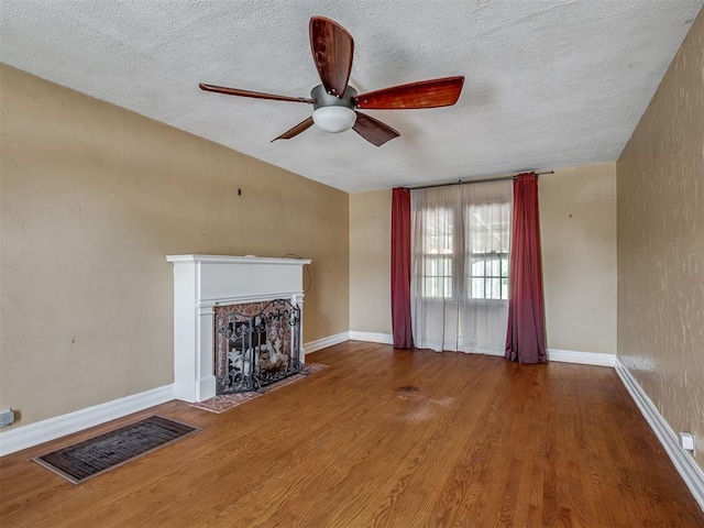 1132 SW 25th St, Oklahoma City, OK 73109 - unfurnished living room with a ceiling fan, a textured ceiling, wood finished floors, a fireplace with flush hearth, and baseboards
