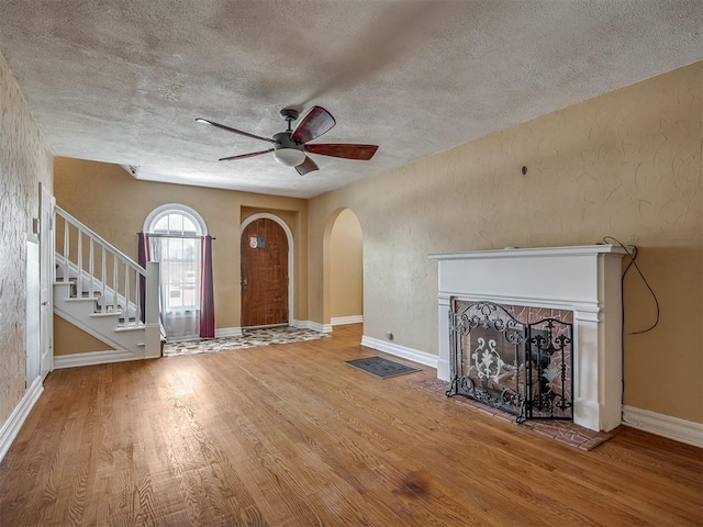 1132 SW 25th St, Oklahoma City, OK 73109 - foyer entrance featuring arched walkways, wood finished floors, a ceiling fan, a textured ceiling, and a fireplace