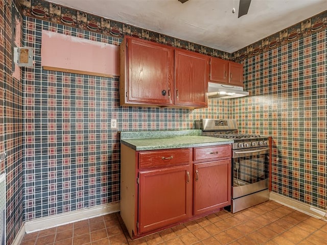1132 SW 25th St, Oklahoma City, OK 73109 - kitchen featuring stainless steel gas range, under cabinet range hood, light tile patterned flooring, ceiling fan, and baseboards