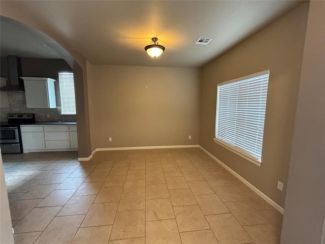 11308 NW 103rd St, Yukon, OK 73099 - unfurnished living room with arched walkways, baseboards, and light tile patterned flooring