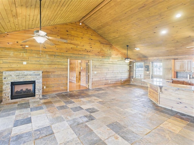 unfurnished living room featuring a ceiling fan, wood ceiling, wooden walls, a fireplace, and stone tile floors