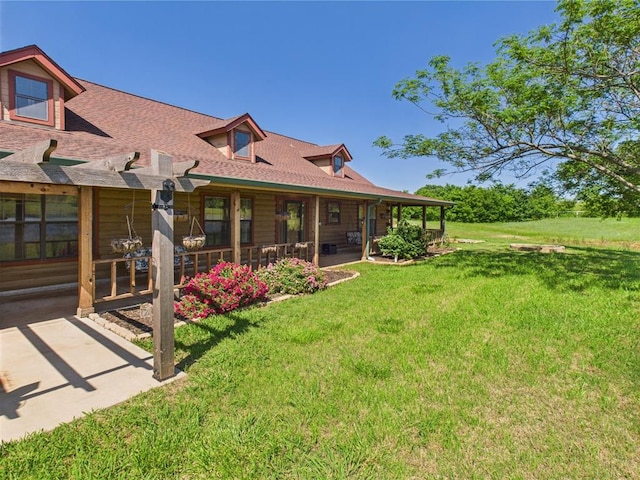 rear view of property featuring a yard, a patio area, and roof with shingles