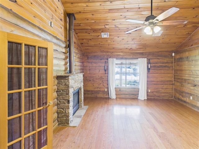 unfurnished living room with lofted ceiling, ceiling fan, wood finished floors, a stone fireplace, and wood ceiling