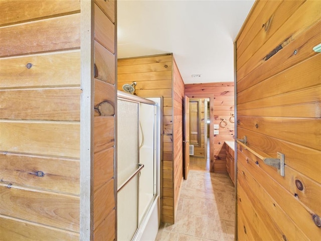full bathroom with wood walls, shower / bath combination with glass door, and tile patterned floors