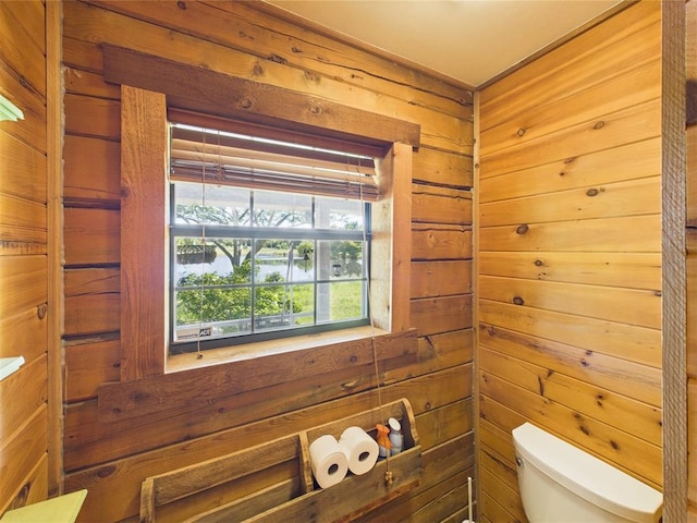 bathroom featuring toilet and wood walls