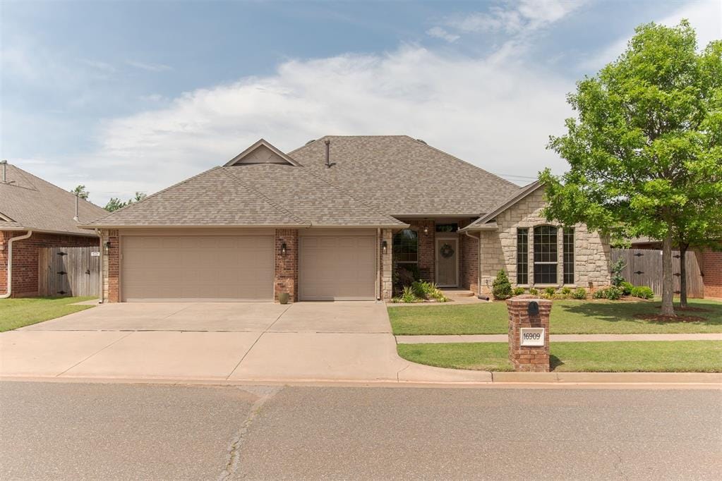 view of front facade with a garage, concrete driveway, a shingled roof, brick siding, and stone siding