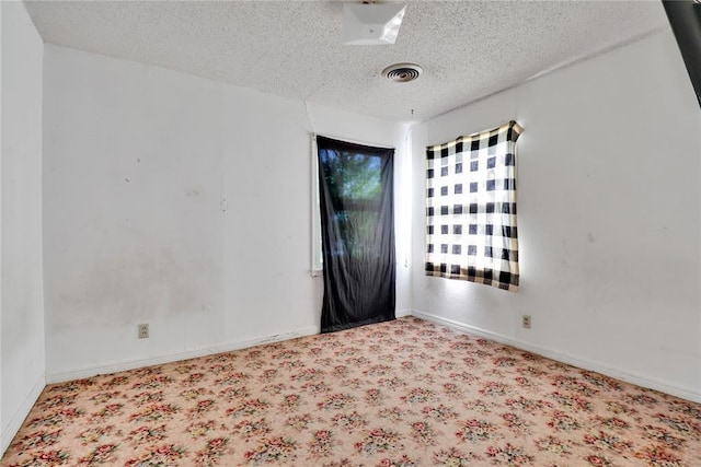empty room with a textured ceiling, carpet floors, and baseboards