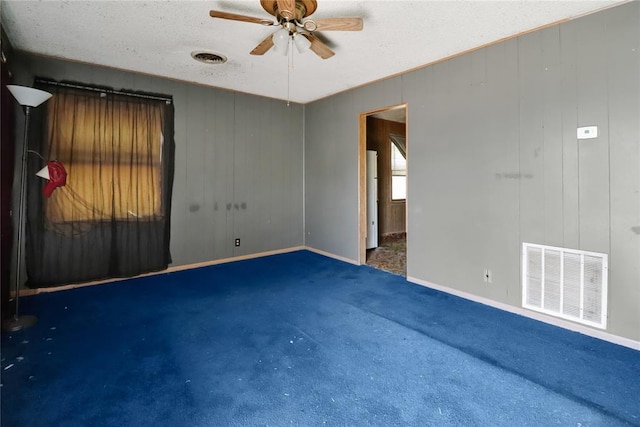empty room with ceiling fan, carpet, baseboards, and a textured ceiling