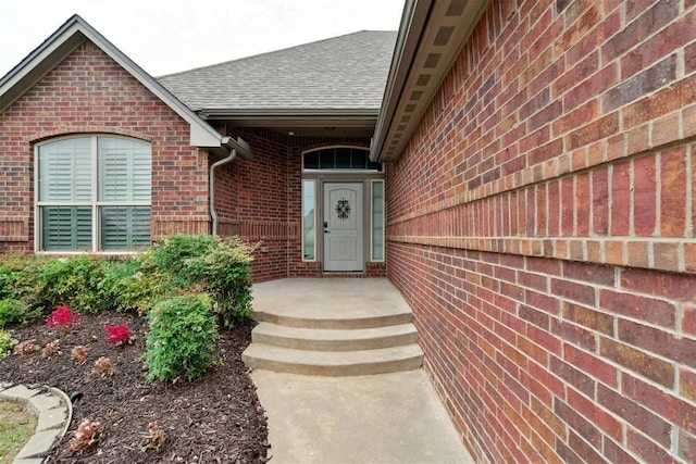 property entrance with brick siding and roof with shingles