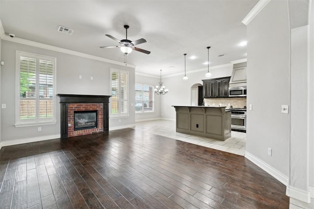 unfurnished living room with ceiling fan, baseboards, light wood finished floors, a chandelier, and crown molding