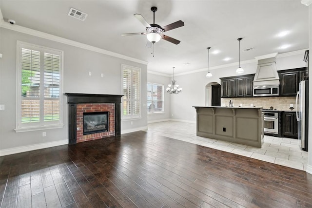kitchen with stainless steel appliances, a fireplace, ceiling fan, open floor plan, and baseboards