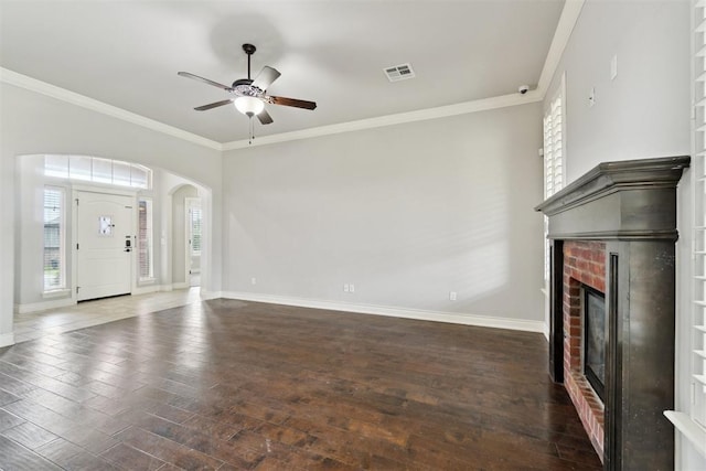 unfurnished living room featuring wood-type flooring, a ceiling fan, baseboards, arched walkways, and a brick fireplace