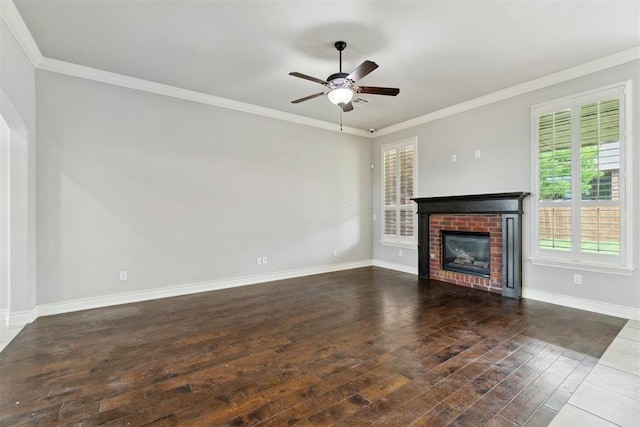 unfurnished living room featuring healthy amount of natural light, hardwood / wood-style floors, ceiling fan, a brick fireplace, and crown molding