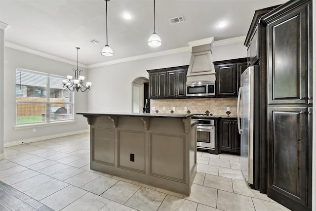 kitchen with appliances with stainless steel finishes, a kitchen breakfast bar, ornamental molding, backsplash, and arched walkways