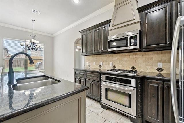 kitchen with stainless steel appliances, a sink, dark brown cabinets, tasteful backsplash, and crown molding