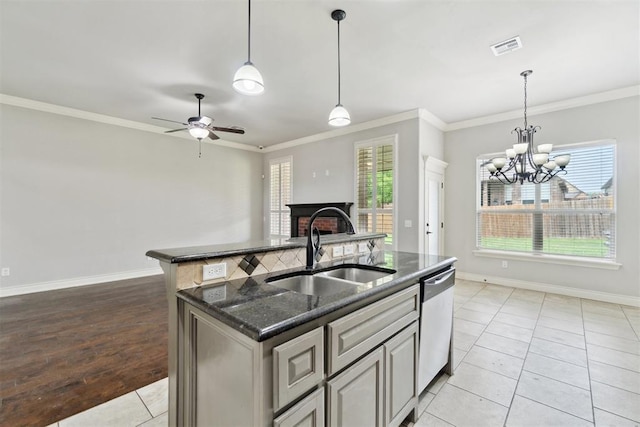 kitchen featuring a sink, ornamental molding, a center island with sink, a fireplace, and baseboards
