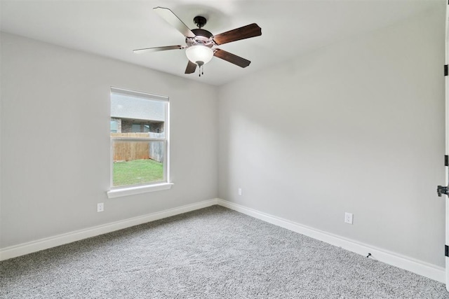 carpeted spare room with a ceiling fan and baseboards