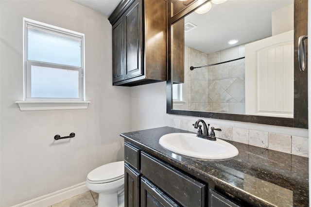 bathroom with toilet, vanity, baseboards, tiled shower, and tile patterned floors