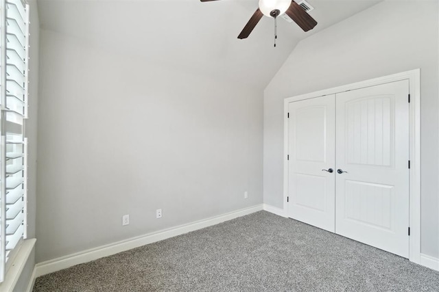 unfurnished bedroom with carpet floors, vaulted ceiling, a closet, baseboards, and a ceiling fan